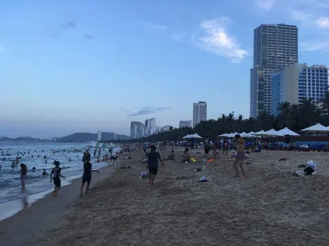 Nha Trang beach at dusk, with hotel towers behind the palms